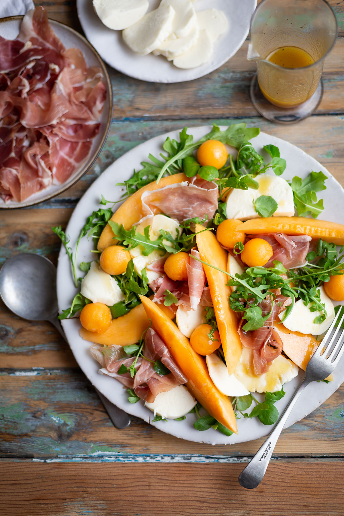 Un grand plateau avec salade de melon, mozzarella et jambon de parme arrangé